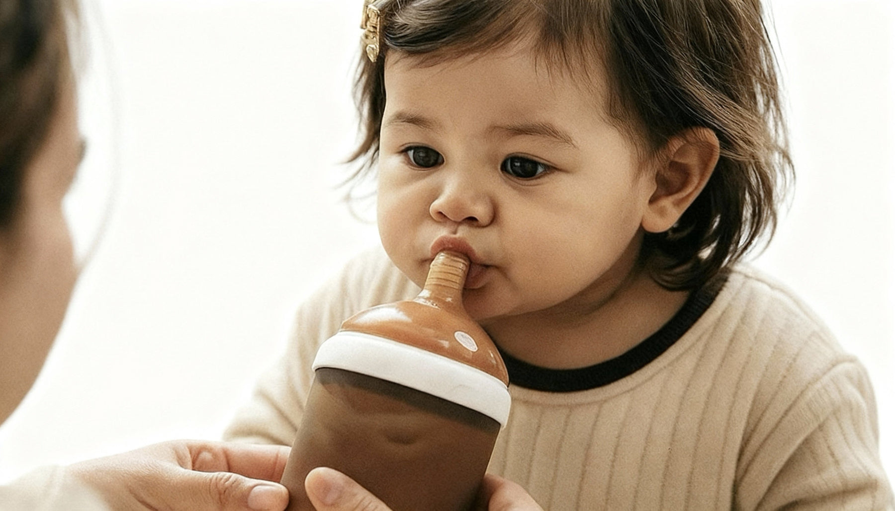 a close up on a sippy cup and a toddlers mouth 